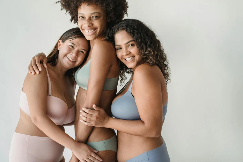 three women in underwear posing for a picture, unsplash, various colors, grey, silicone skin, smiling confidently