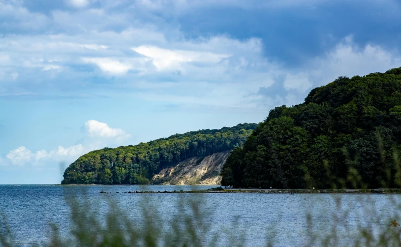 a large body of water surrounded by trees, by Carey Morris, pexels contest winner, upon a peak in darien, high cliff, thumbnail, summertime