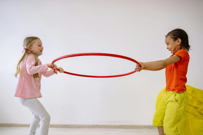 two little girls playing with a hula hoop, by Nina Hamnett, pexels contest winner, interactive art, sport game, still frame, full lenght, indoor picture