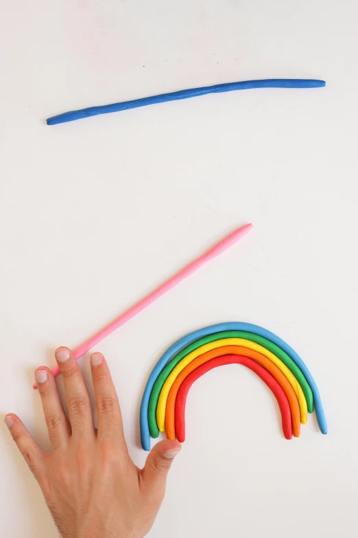 a person is making a rainbow out of plastic straws, a child's drawing, made out of clay, holding a whip, with a white background, different sizes