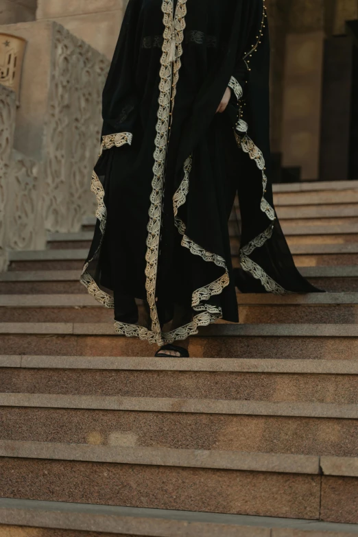 a woman standing on the steps of a building, an album cover, inspired by Modest Urgell, pexels contest winner, arabesque, in dark robes with gold accents, walking down, arab, morning detail