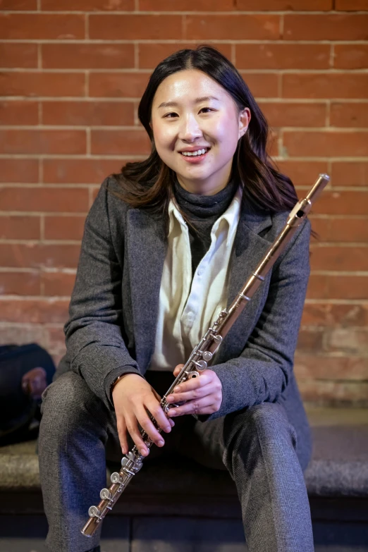 a woman sitting on a bench holding a flute, leslie zhang, portrait image, engineer, ( ( emma lindstrom ) )