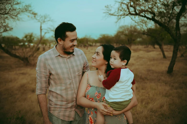 a man and woman holding a child in a field, pexels contest winner, hispanic, avatar image, background image, handsome man