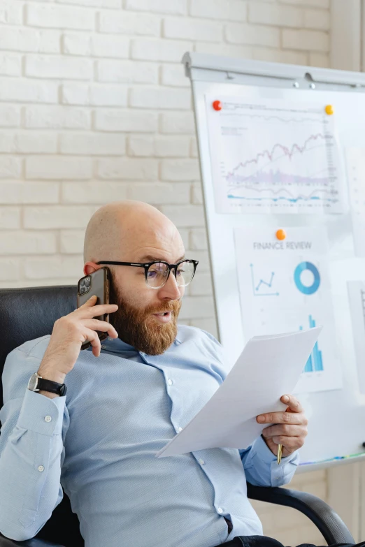 a man sitting in a chair talking on a cell phone, a cartoon, trending on pexels, analytical art, papers on table, ginger bearded man with glasses, analysis report, cool marketing photo