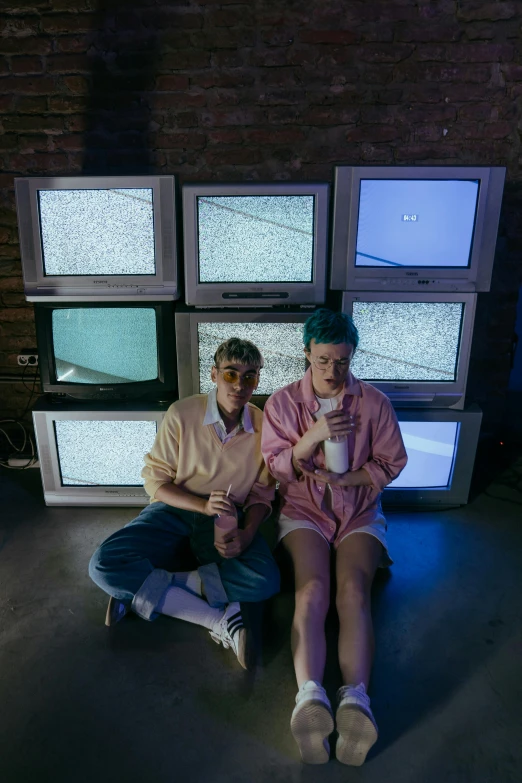 two people sitting in front of a wall of televisions, an album cover, inspired by Elsa Bleda, unsplash, video art, lil peep, milk bar magazine, lesbians, sophia lillis