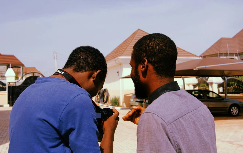 a couple of men standing next to each other, a picture, by Chinwe Chukwuogo-Roy, pexels contest winner, home video footage, behind the scenes, bottom angle, camera
