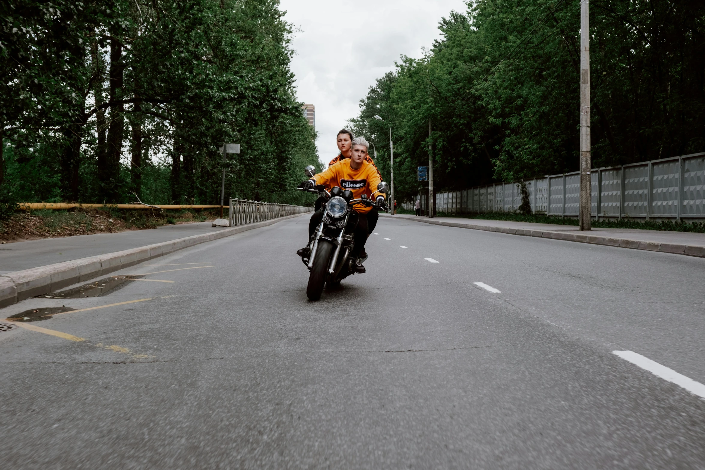 a man riding on the back of a motorcycle down a street, by Adam Marczyński, pexels contest winner, excited russians, medium shot of two characters, yellow, college