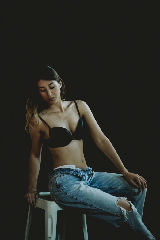 a woman in a bra top sitting on a stool, inspired by Elsa Bleda, trending on pexels, ( ( ( wearing jeans ) ) ), 🤤 girl portrait, night, androgynous person