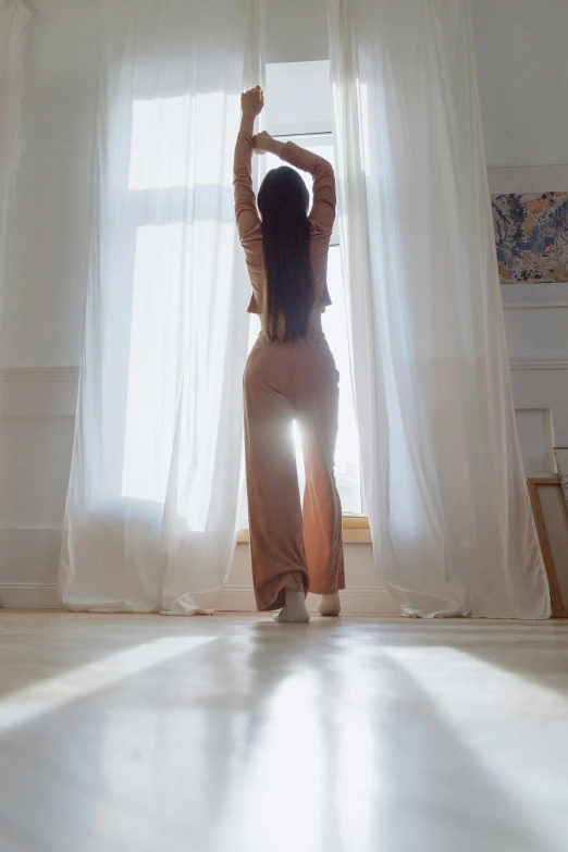 a woman that is standing in front of a window, trending on pexels, arabesque, soft morning light. hyperrealism, shapely derriere, wearing a baggy pajamas, with long hair