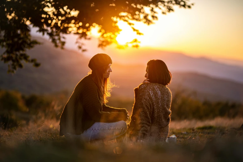 two women sitting under a tree at sunset, pexels contest winner, profile image, warm light, picnic, looking off into the distance