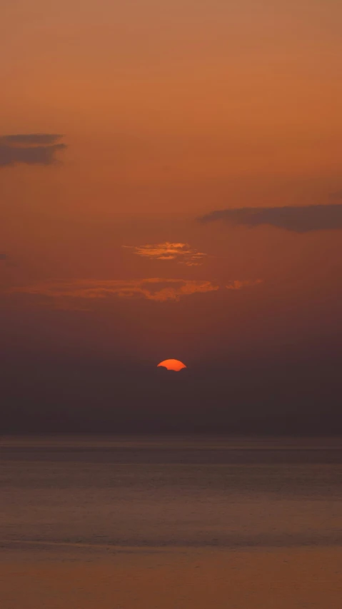 the sun is setting on the horizon of the ocean, by Attila Meszlenyi, high quality image, trending photo, bali, red moon