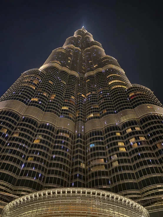 a very tall building lit up at night, sheikh, towering high up over your view, huge spines, exterior shot