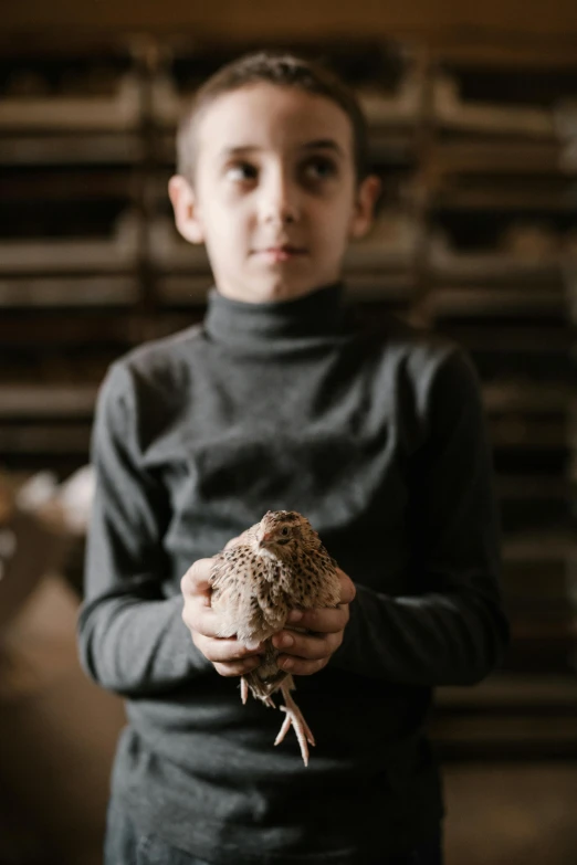 a young boy holding a piece of food in his hands, an album cover, by Jan Tengnagel, pexels contest winner, chicken, ignant, 14 yo berber boy, a wooden