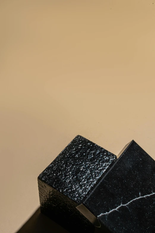 a couple of black boxes sitting on top of a table, an abstract sculpture, by Attila Meszlenyi, unsplash, high texture detail, detailed product image, glittery short black hair, detailed product shot