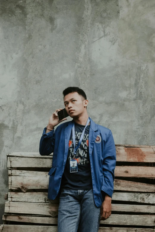 a man sitting on a wooden bench talking on a cell phone, an album cover, inspired by Rudy Siswanto, pexels contest winner, wearing blue jacket, posing for a picture, batik, security agent