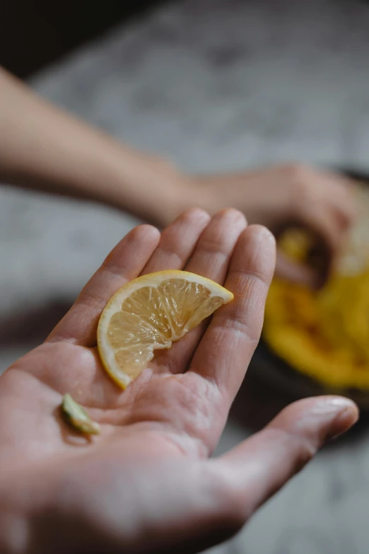 a person holding a slice of lemon in their hand, by Julia Pishtar, trending on pexels, renaissance, making a potion, anjali mudra, handcrafted, flattened