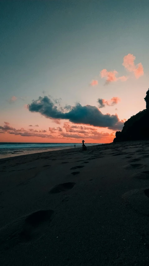 a sunset on a beach with footprints in the sand, by Jesper Knudsen, unsplash contest winner, cliffs, lone person in the distance, bali, trending on vsco