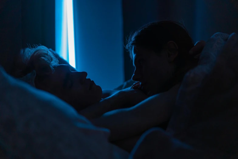 a man and a woman laying in bed next to each other, by Elsa Bleda, serial art, blue backlight, lesbian embrace, scene from live action movie, instagram photo