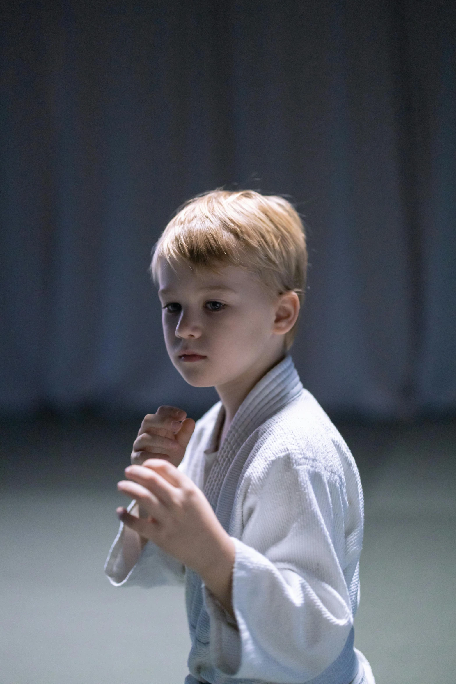 a young boy standing on a tennis court holding a tennis racquet, a picture, unsplash, happening, aikido, mma southpaw stance, portrait of small, in a dojo