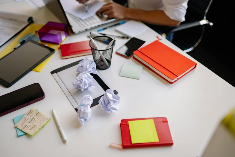 a person sitting at a desk working on a laptop, by Julia Pishtar, pexels contest winner, with a bunch of stuff, paper origami, 9 9 designs, schools