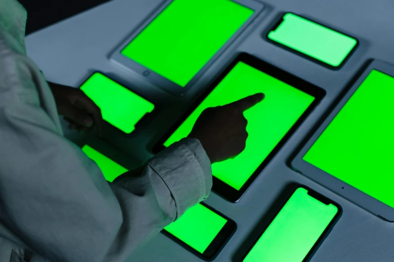 a person using a cell phone with a green screen, a digital rendering, inspired by Joseph Wright of Derby, interactive art, softly glowing control panels, handling laboratory equipment, trending on dezeen, using a magical tablet