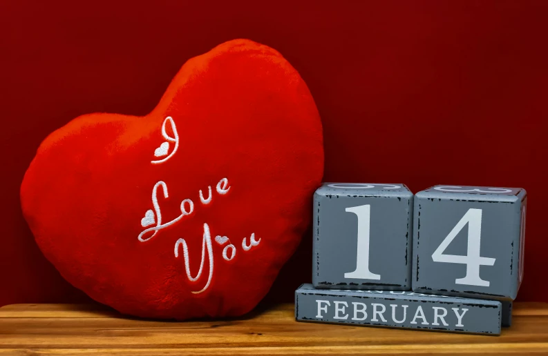 a red heart sitting on top of a wooden table, cushions, date, product display photograph, engraved