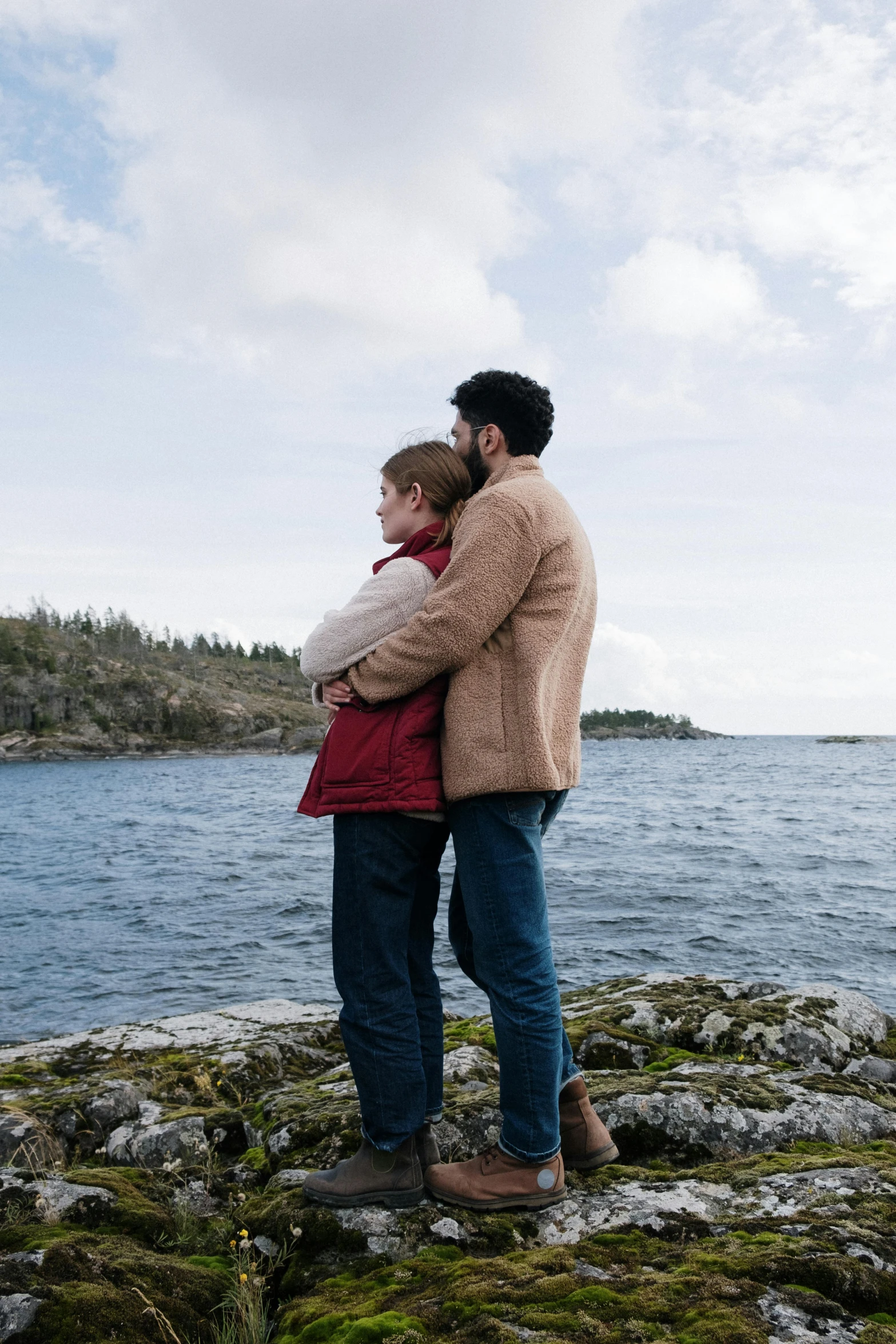 a man and a woman standing on a rock by the water, two men hugging, netflix, overlooking the ocean, julia hetta