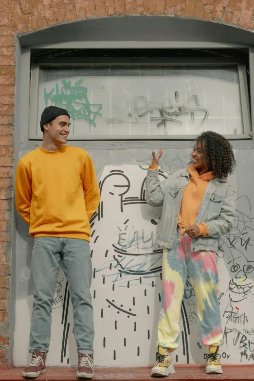 a couple of people that are standing in front of a door, a cartoon, trending on pexels, graffiti, long orange sweatshirt, colors: yellow, color footage, commercial