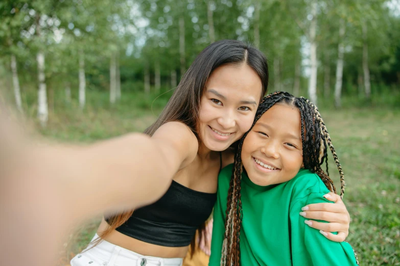 a woman taking a selfie with a young girl, pexels contest winner, green and brown clothes, avatar image, young asian girl, black teenage girl