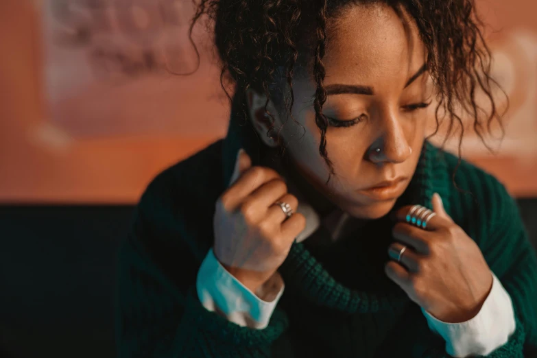 a woman in a green sweater adjusts her tie, trending on pexels, visual art, mixed race woman, extremely moody blue lighting, resting head on hands, ashteroth