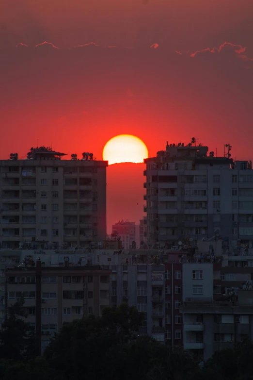 the sun is setting over the city skyline, pexels contest winner, turkey, big red sun, stacked image, backlite