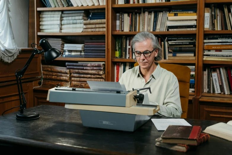 a man sitting at a desk typing on a typewriter, jimmy page, with one vintage book on a table, quicksilver, julia hetta