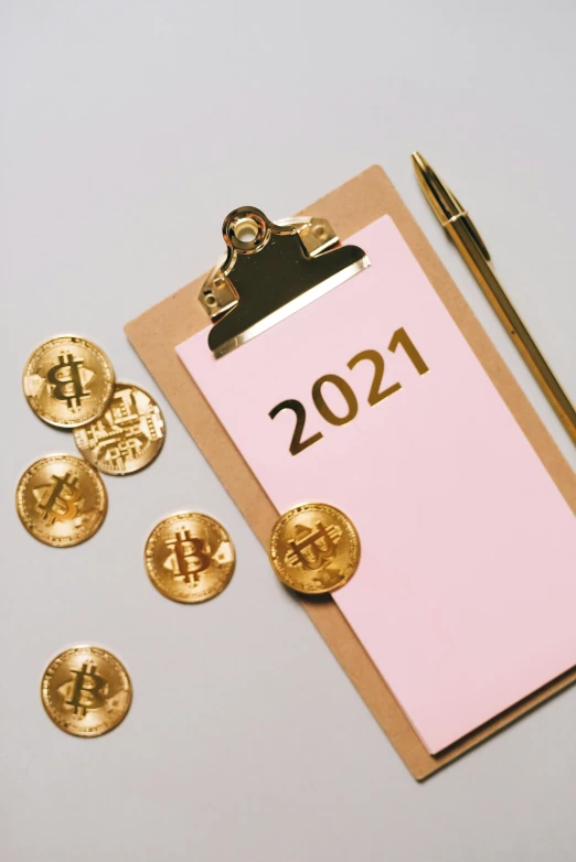 a clipboard with coins and a pen next to it, by Julia Pishtar, happening, 2021, bitcoin, new years eve, thumbnail