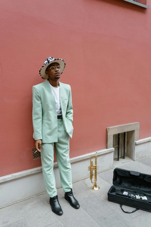 a man in a green suit standing next to a red wall, trending on pexels, renaissance, wearing straw hat, maria borges, wearing a light blue suit, in style of juergen teller