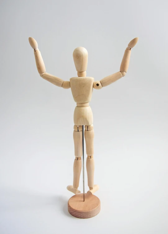 a wooden mannequin standing on a wooden base, inspired by Leonardo da Vinci, pose(arms up + happy), 5 points of articulation, fully posable, ball jointed doll