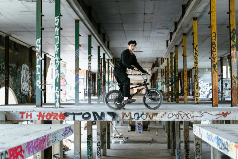 a man riding a bike on top of a wooden platform, a portrait, inspired by Seb McKinnon, in a warehouse, boys, press shot, leng jun