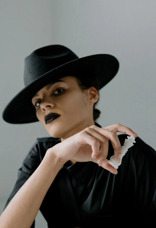 a woman wearing a black hat and a black dress, inspired by Romaine Brooks, pexels contest winner, chewing tobacco, off - white collection, ameera al-taweel, resin