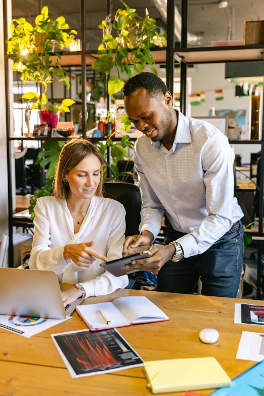 a couple of people that are sitting at a table, working in an office, holding a clipboard, varying ethnicities, standing on a desk