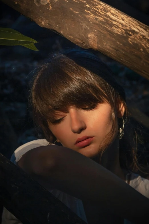 a woman sitting on top of a wooden bench, an album cover, inspired by Elsa Bleda, trending on pexels, exhausted face close up, laying under a tree on a farm, brown hair and bangs, alexey gurylev