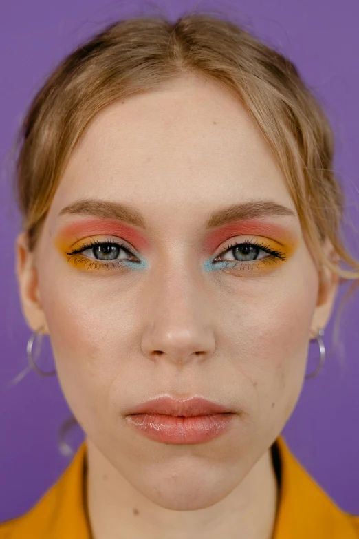 a woman with colorful makeup looks at the camera, inspired by Louisa Matthíasdóttir, trending on pexels, color field, sydney sweeney, yellow purple, frontal shot, close body shot