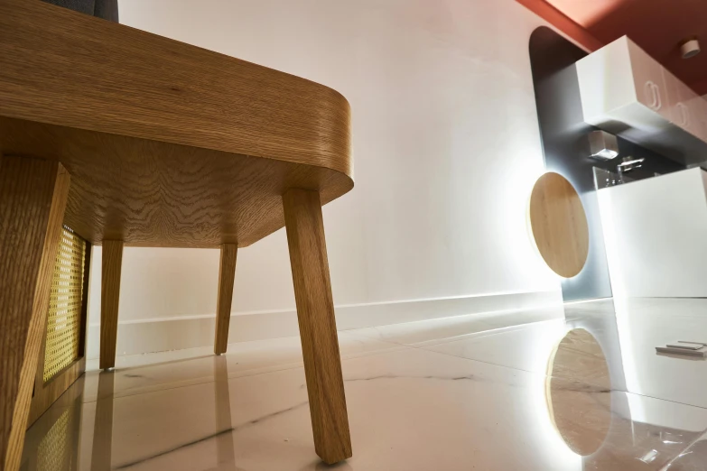 a wooden table sitting on top of a white floor, inspired by Isamu Noguchi, pexels contest winner, light and space, lit from below with red lighting, two plastic chair behind a table, closeup - view, light wood