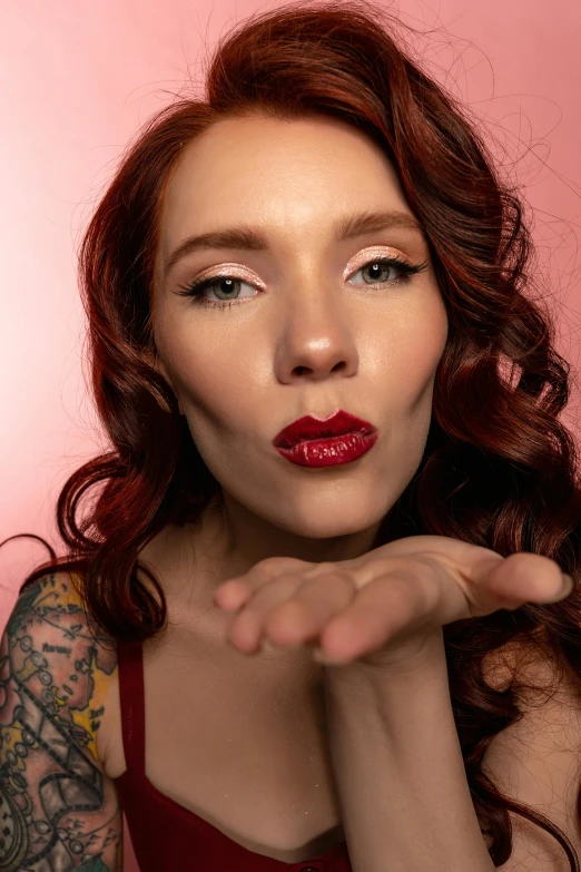 a woman making a heart sign with her hands, an album cover, by Jesse Richards, trending on pexels, photorealism, luscious lips, tattooed pinup, ( redhead, closeup headshot