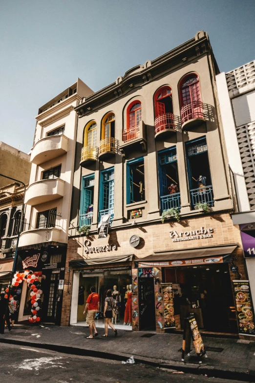 a group of people walking down a street next to tall buildings, art nouveau, colorful caparisons, buenos aires, stores, non-binary