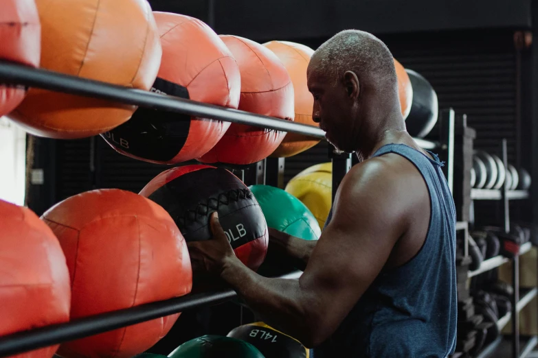 a man working on medicine balls in a gym, a portrait, by Meredith Dillman, pexels contest winner, black man, manuka, full of colour, profile picture