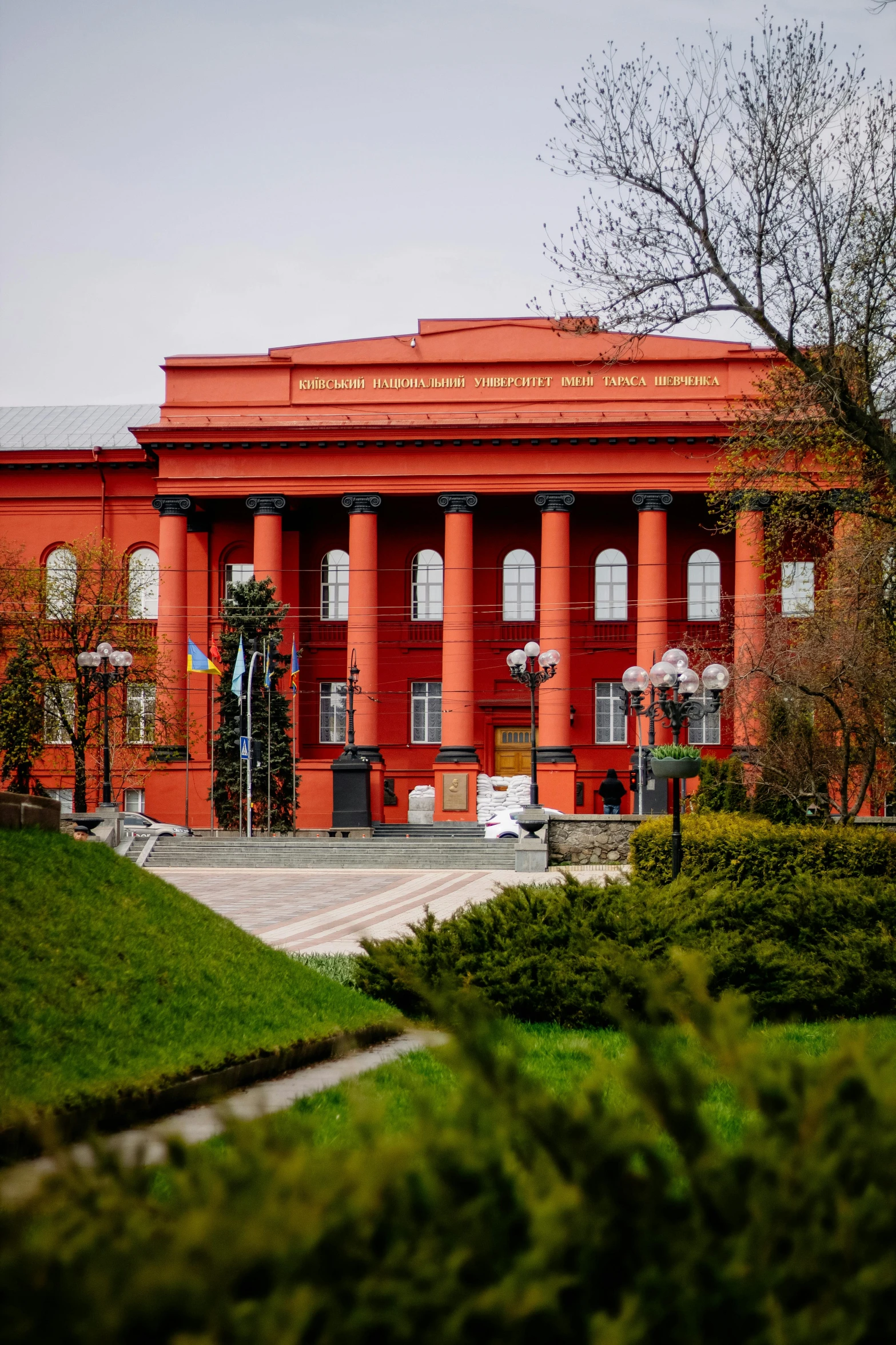 a large red building sitting on top of a lush green field, a picture, by Serhii Vasylkivsky, academic art, archs and columns, ukraine. photography, archive photo, multiple stories