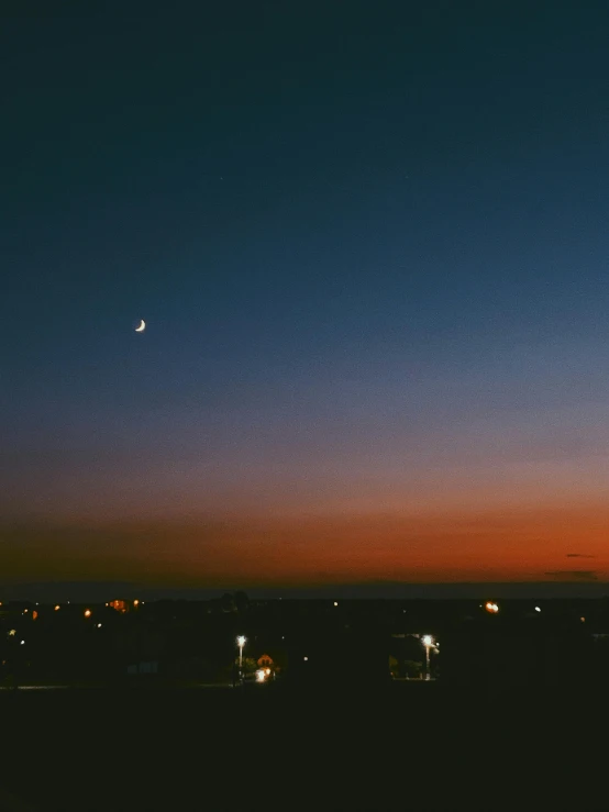 a view of a city at night with the moon in the sky, an album cover, unsplash contest winner, ☁🌪🌙👩🏾, summer sunset, dusk on jupiter, 3 5 mm photo