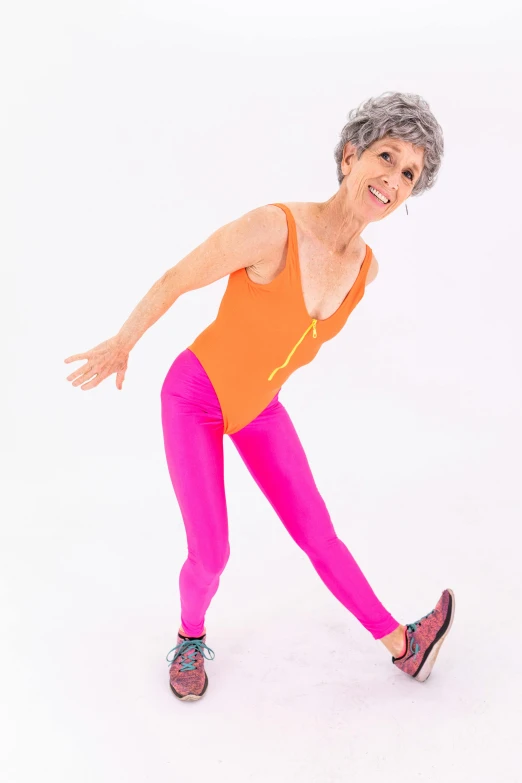 a woman in a bright orange top and pink leggings, by Pamela Drew, arabesque, she is about 7 0 years old, model is wearing techtical vest, thin bodysuit, elizabeth saltzman