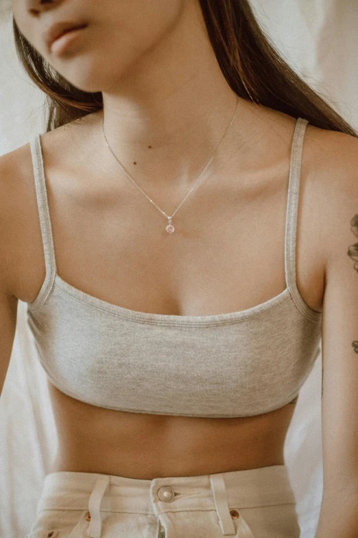 a woman with a tattoo on her arm, a colorized photo, inspired by Elsa Bleda, trending on pexels, physical : tinyest midriff ever, silver necklace, cozy aesthetic, minimal pink palette