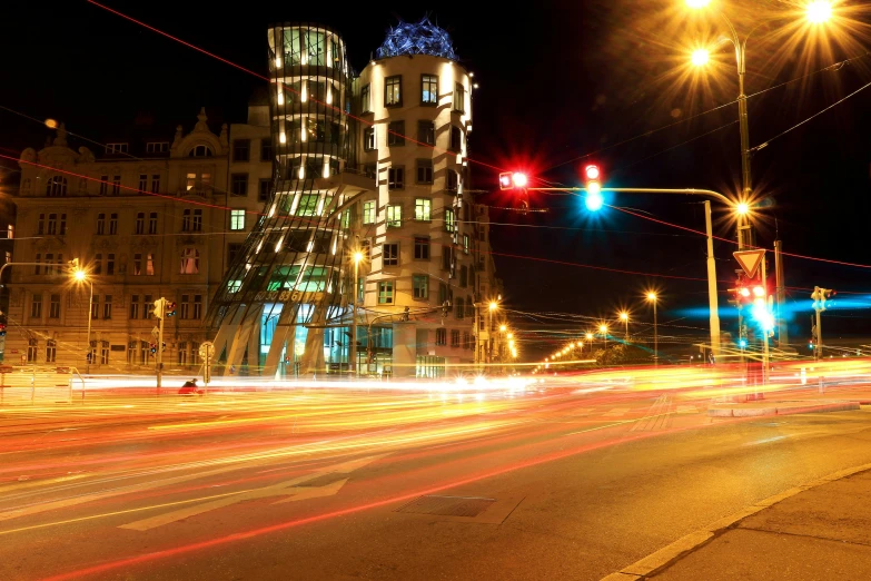 a very tall building sitting on the side of a road, by Adam Marczyński, pexels contest winner, art nouveau, frank gehry, nightlife, slide show, howl\'s moving castle at night