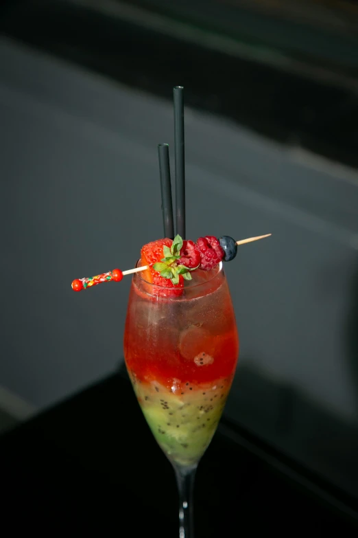 a close up of a drink in a glass on a table, red and green color scheme, skewer, birdseye view, infused with aurora borealis